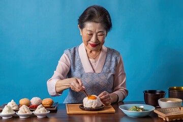 Senior Asian woman preparing a traditional dessert, with a warm expression