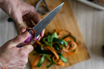 a man peeling off a variety of vegetables such as cucumber, onion, carrot, into the cutting board...