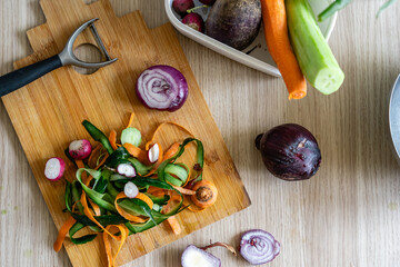 a man peeling off a variety of vegetables such as cucumber, onion, carrot, into the cutting board...