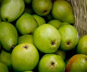 Pears stacked inside a basket in a food market stall, close-up.
