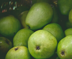 Pears stacked inside a basket in a food market stall, close-up.