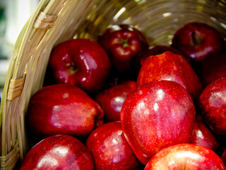 A wooden basket filed with red apples, close-up.