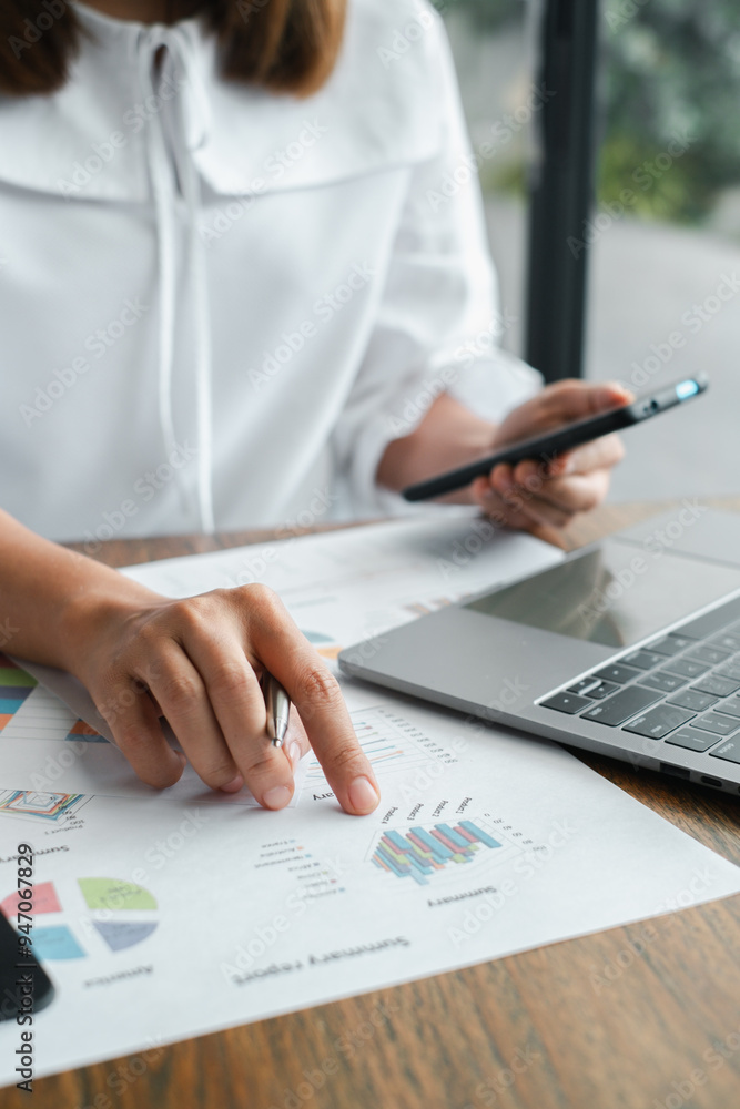 Poster close-up of a business professional analyzing financial charts and graphs with a laptop and smartpho