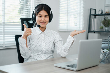 Professional woman in a white shirt giving a thumbs up while working from home with a headset and...