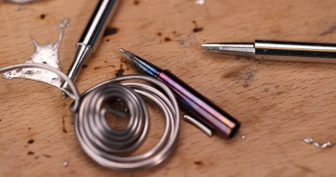 whole and molten solder and soldering iron tip on the board, solder and soldering iron tips scattered on the beech board