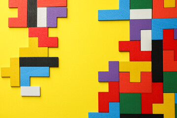 Colorful wooden puzzle pieces on yellow background, top view