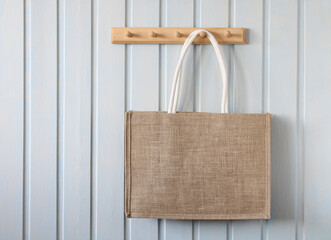 simple eco-friendly burlap bag hangs on a white wall on a wooden hanger. the concept is without...