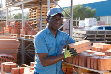 Portrait african american worker lays bricks in an open air warehouse
