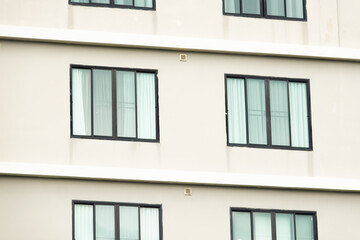 A building with many windows and a white wall. The windows are mostly clear and the building appears to be empty