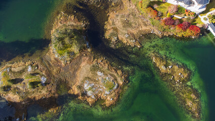Aerial view of a rocky outcrop showing above the shallow sea during low tide