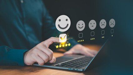 Customer selects a happy smile face icon on a virtual screen on a laptop, signaling satisfaction in service. Concept of assessment, testimonial, customer service feedback, and opinion rating.