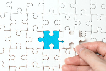 Top view hand holding flat lay of white jigsaw puzzle to connecting game texture incomplete or...