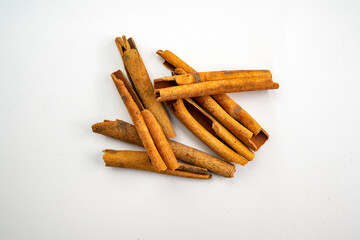 A pile of cinnamon sticks on a white surface