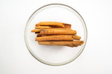 A bowl of cinnamon sticks sits on a white background