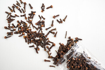 A bag of ground cloves is spread out on a white surface