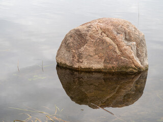 Large boulder on lake or river. Boulder with its reflection in the calm water. Ecological problems © Gunars