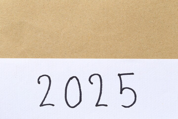 Numbers two thousand twenty-five are hand-written on white art paper background.