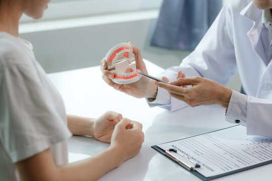 A dentist advises a patient on dental care in a modern clinic, explaining oral hygiene and treatment options with tools or diagrams.