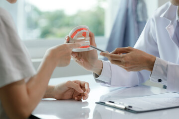 A dentist advises a patient on dental care in a modern clinic, explaining oral hygiene and...