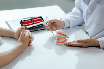 A dentist advises a patient on dental care in a modern clinic, explaining oral hygiene and...