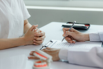 A dentist advises a patient on dental care in a modern clinic, explaining oral hygiene and...