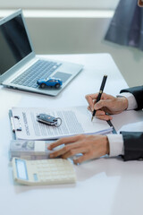 A car salesman in the middle of offering a vehicle and signing a contract.
