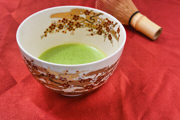 日本の茶道　茶碗と茶筅と抹茶 赤背景　コピースペースあり　Japanese Tea Ceremony (Chado) : Tea bowl, tea whisk and matcha (green tea) on red background, copy space available
