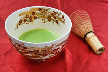 日本の茶道　茶碗と茶筅と抹茶 赤背景　コピースペースあり　Japanese Tea Ceremony (Chado) : Tea bowl, tea whisk and matcha (green tea) on red background, copy space available
