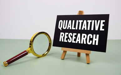 Qualitative Research text on paper card with magnifying glass on green background