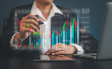 Businessman or trader is showing a growing virtual hologram stock on taplet and laptop with analysing virtual trading price graph 