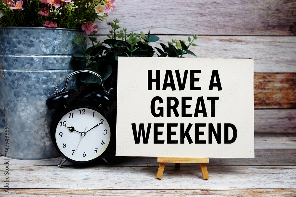 Wall mural have a great weekend text on paper card and easel standing with alarm clock on wooden background