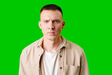 Obraz premium Young Man Posing With Serious Expression Against Bright Green Background