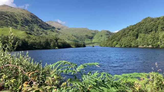 Western highlands Scottish loch on a stunning summer blue sky day with mountains and white clouds