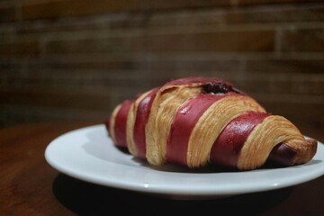 Freshly baked croissants with raspberry jam on a white plate on a wooden table. Healthy eating concept. Organic farm products for breakfast or lunch.