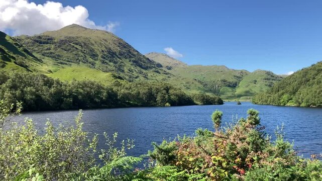 Western highlands Scottish loch on a stunning summer blue sky day with mountains and white clouds
