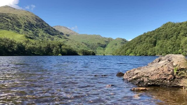 Western highlands Scottish loch on a stunning summer blue sky day with mountains and white clouds