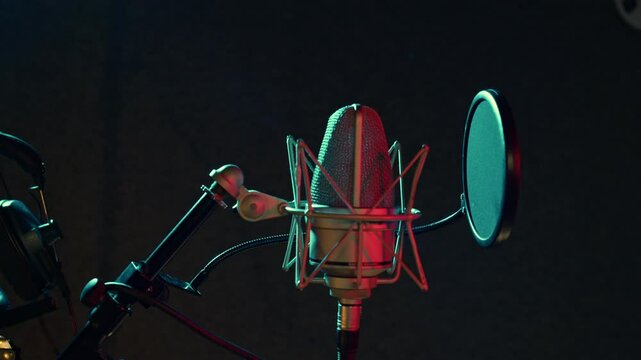 Professional microphone is in dark recording hall. Sound department with musical equipment. Audio studio for radio broadcast, production of hit songs, phonogram, singer albums. Teal and orange