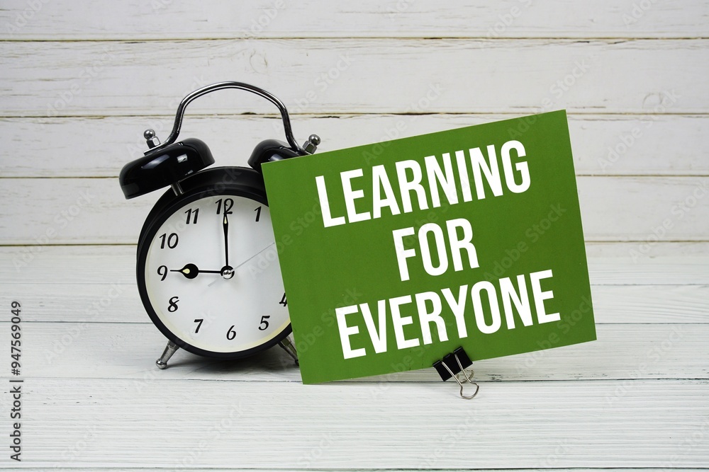 Poster learning for everyone text message on paper card with alarm clcok on wooden background