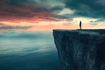 Silhouette of person standing on cliff edge at dusk