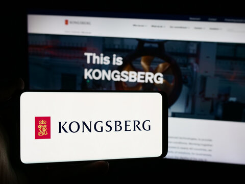 Stuttgart, Germany - 08-20-2024: Person holding mobile phone with logo of Norwegian company Kongsberg Gruppen ASA in front of business web page. Focus on phone display.