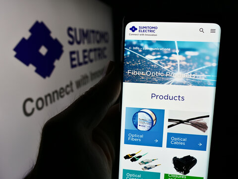 Stuttgart, Germany - 08-21-2024: Person holding cellphone with webpage of Japanese company Sumitomo Electric Industries Ltd. in front of logo. Focus on center of phone display.