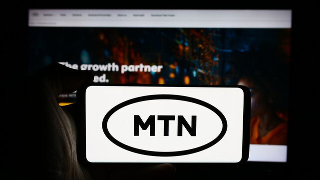 Stuttgart, Germany - 08-21-2024: Person holding cellphone with logo of South African telecommunications company MTN Group Limited in front of webpage. Focus on phone display.