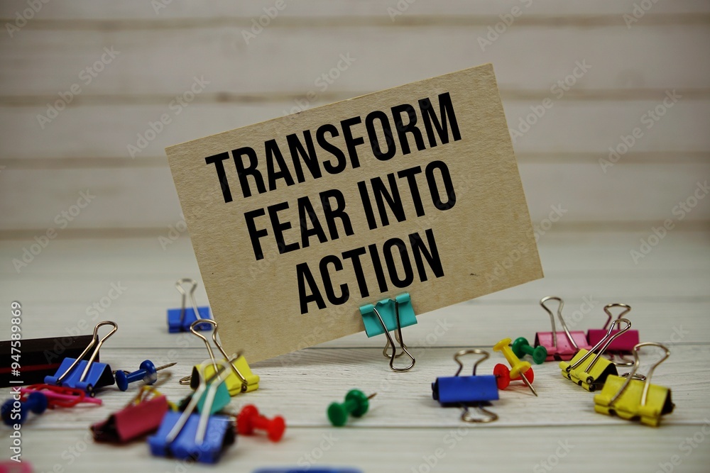 Poster transform fear into action text on paper card with stationary on wooden background