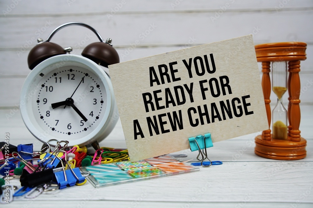 Poster are you ready for a new change? text on paper card with alarm clock and stationary on wooden backgro
