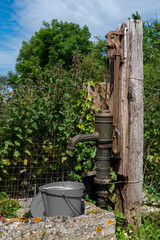 Obraz premium A rusty old water pump is sitting next to a bucket