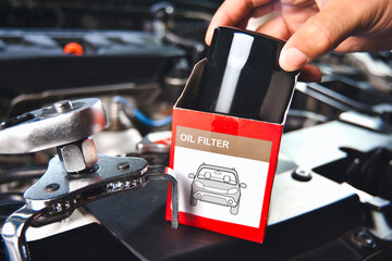 A car mechanic hand is unpacking a new oil filter to replace it , New oil filter in the hands of an car mechanic , Car maintenance concept
