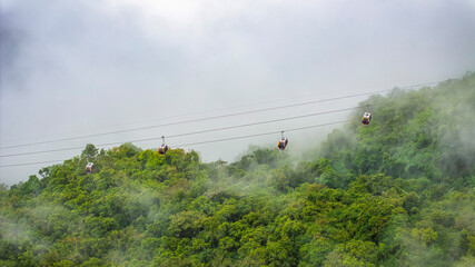 Ba Den mountain tourist area. The longest cable car at Ba Den mountain in cloud sky. Below is forest.