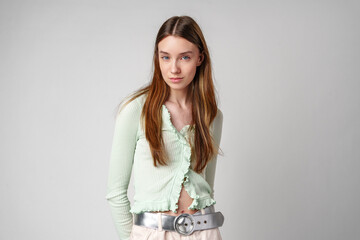 Woman in Green Cardigan and Beige Cargo Pants Poses Against a White Wall
