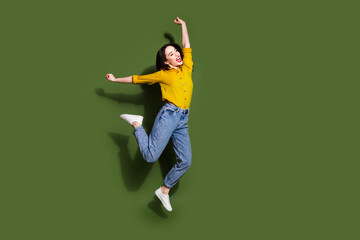 Full length photo of shiny attractive lady dressed yellow blouse jumping high empty space isolated green color background