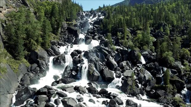 Aerial view of the cascading Uchar waterfall on the Chulcha River, flowing over rocks and pine forests. Beautiful wildlife in the Altai Mountains
